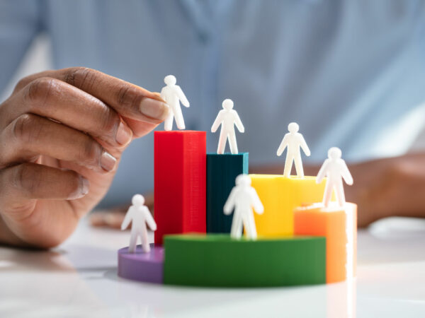 Businesswoman Placing Human Figures On 3d Pie Chart